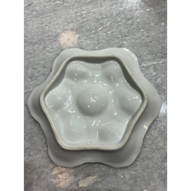 A distinctive antique French porcelain oyster plate featuring six deeply sculpted, shell-form wells arranged around a...