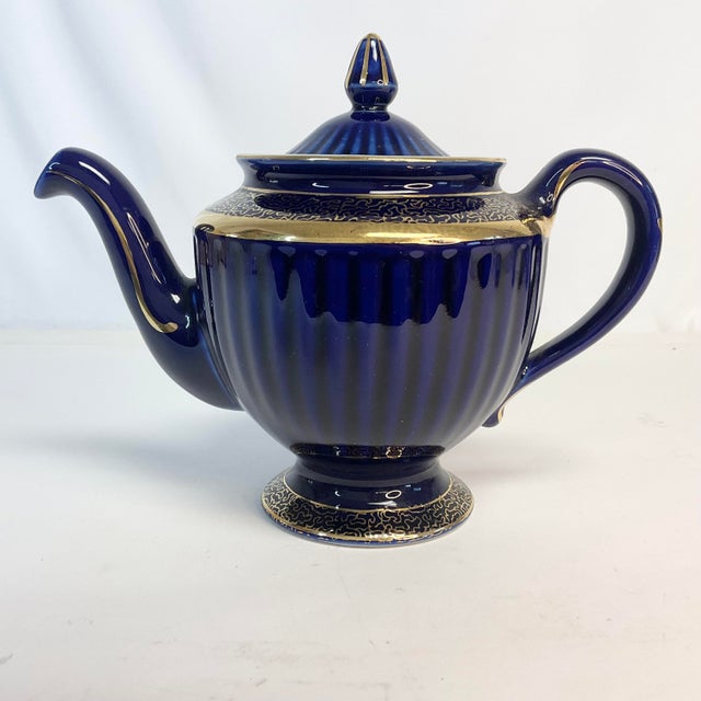 Offering a 6-cup Hall Pottery Ceramic Tea Pot. This is in the Art Deco style of Cobalt Blue with a Gold band accent. It...