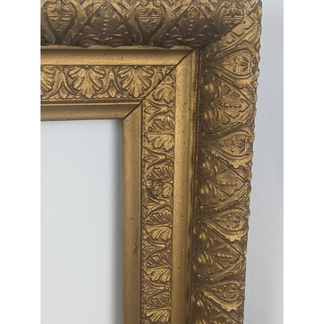 A beautifully detailed early 20th century gilt picture frame featuring a substantial, multi-layered architectural profile...