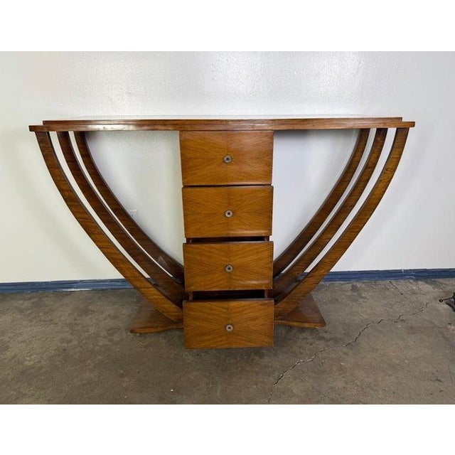 This striking Art Deco console features a bold, symmetrical silhouette centered around a vertical stack of four drawers...