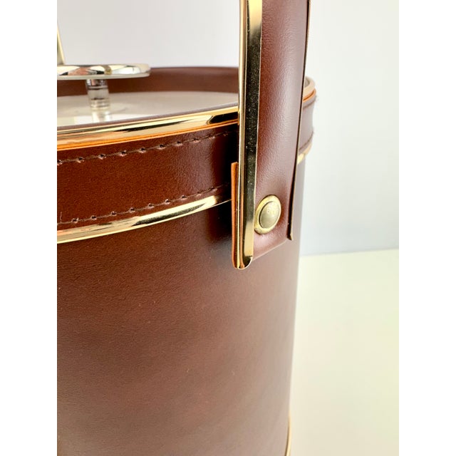 A vintage mid century cocktail ice bucket finished in rich brown leatherette with stitched detailing and polished gold-...
