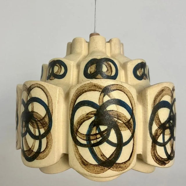 An exquisite hanging lamp with an unusual shape, made with rich colored ceramic with the shape of a flower in darker...
