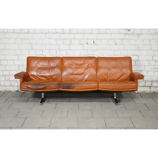 Vintage three-seat DS-31 sofa produced by De Sede in Switzerland during the 1970s. The sofa is upholstered in rich cognac-...