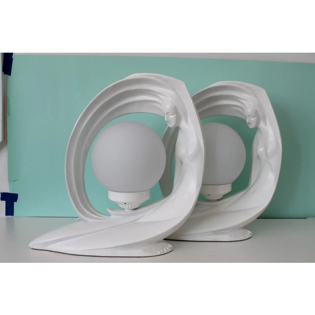 Awesomely 80's orb table lamp pair. Nude woman figure creates a circle with her hair and body to nestle the orb in the...