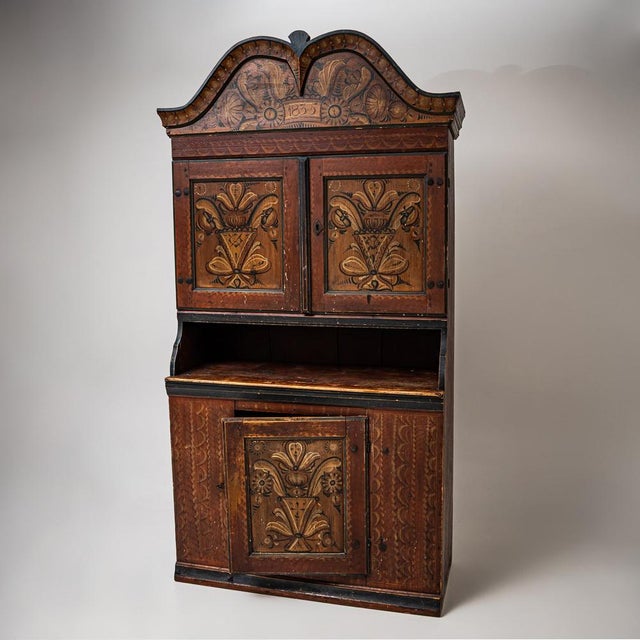 Hand-painted folk armoire in pine with two-door upper section, open shelf area, and lower door compartment. Red-ground...