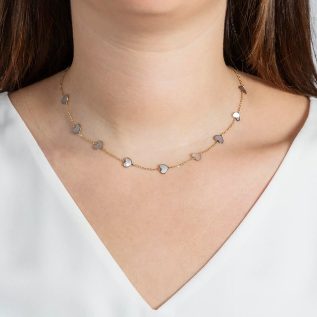 A chic way to add a pop of white and "heart" to your neck stack. Nine Mother of Pearl hearts with gold chain in between...