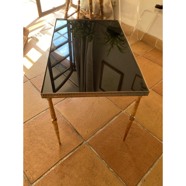 Neoclassical style coffee table from the 1930s/40s. The table legs are made of solid brass, and the frame is topped with...