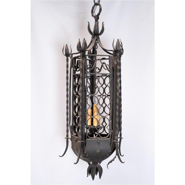 A tall, wrought iron lantern, late 19th century, French. Lantern is five-sided with open, quatrefoil-motif ironwork and...