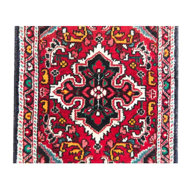 An early 20th century Persian Hamadan rug with a central floral medallion amidst a field of scrolling vines and flowers,...