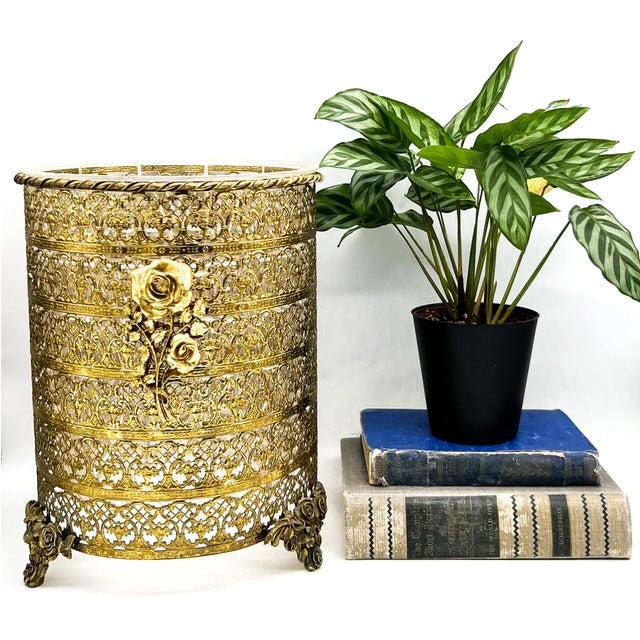 Elegant, vintage brass wastebasket featuring intricate pierced filigree, sculptural rose appliqués, and ornate rose-form...