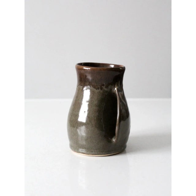 This is a vintage studio pottery mug. Signed by the artist, the handmade hand-warmer mug features an inset handle and...