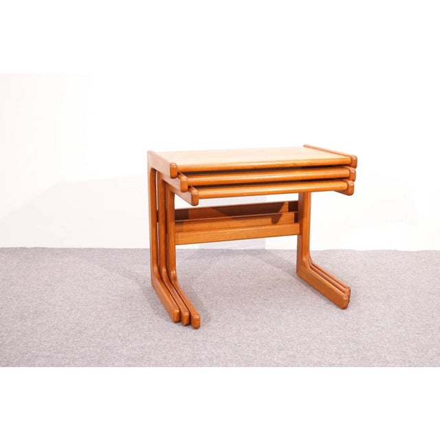 This is a set of three Scandinavian modern teak nesting tables. The tables are made of solid teak and have rounded edges.