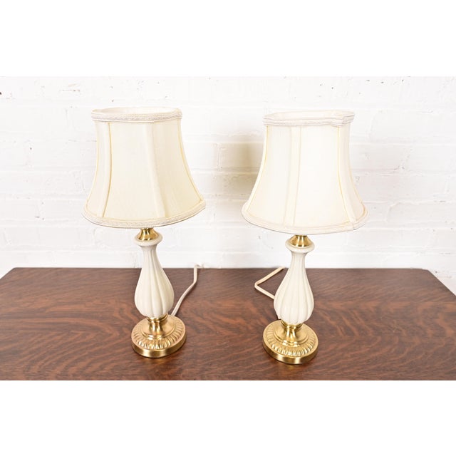 A gorgeous pair of Hollywood Regency porcelain and brass table lamps By Lenox Lighting by Quoizel Circa Late 20th Century...