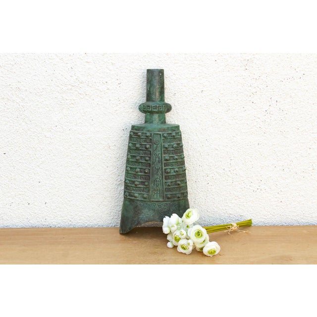 This heavy-cast bronze bell is a remarkable study in archaic ritual design, featuring the characteristic "ni" (bosses) and...