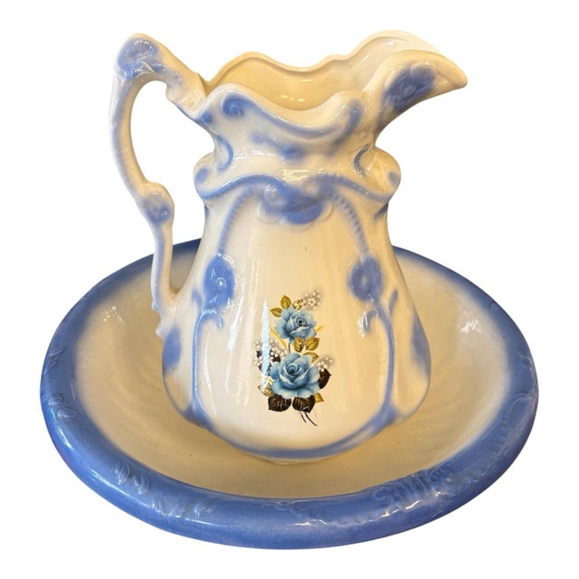 An exceptionally decorative early 20th-century ceramic wash basin and pitcher set in soft ivory and periwinkle blue. The...