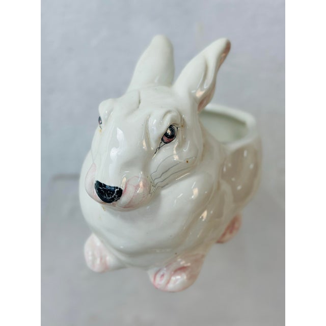 This is a vintage ceramic rabbit planter with a glossy white glaze. The planter is sculpted in the shape of a sitting...