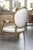 This is one of a pair of identical Louis XVI-style giltwood arm chairs with a gracefully shaped oval medallion back and...