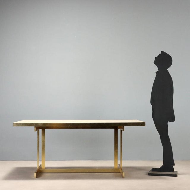 1980s table featuring a brass base that adds a touch of brilliance to the overall design. The light laminate rectangular...