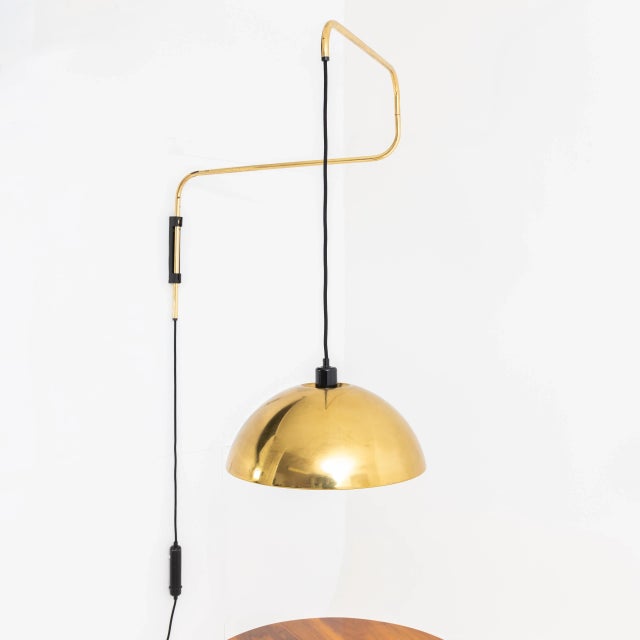 Italian wall lamp made of brass with pivot arm and black cable hanging down lampshade (ø40 cm). The switch functions as a...
