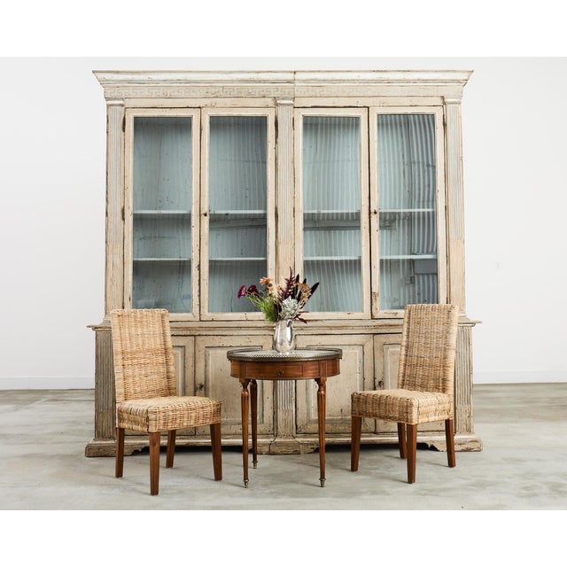 Imposing 19th century French library bookcase or cabinet featuring a weathered, painted finish. The two-part case is...