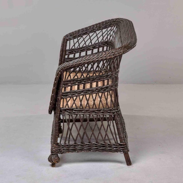 A wicker settee showcasing intricate diamond lattice weave throughout back and arms. Features gracefully rolled arms,...