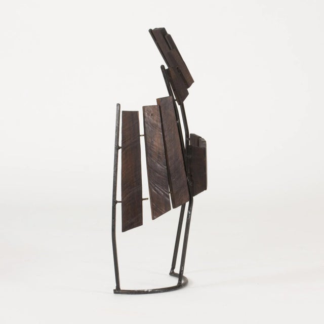 Striking sculpture by Fred Leyman, made with dark stained wood arranged on a black lacquered metal frame that is arched in...