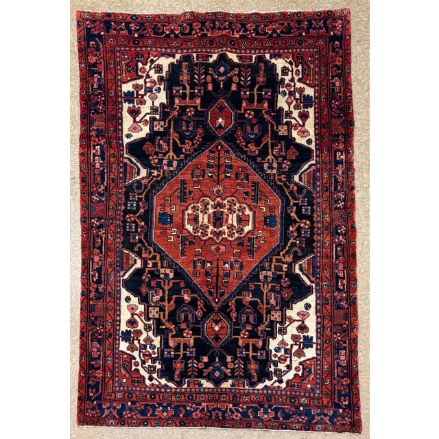 Antique hand-knotted rug from the Nahavand region of western Iran, featuring a bold central diamond medallion set within a...