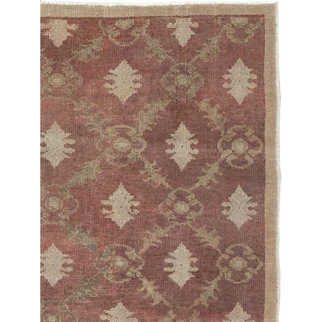 This mid-20th-century Turkish Anatolian throw rug presents an elegant allover composition across a muted dusty-rose field....