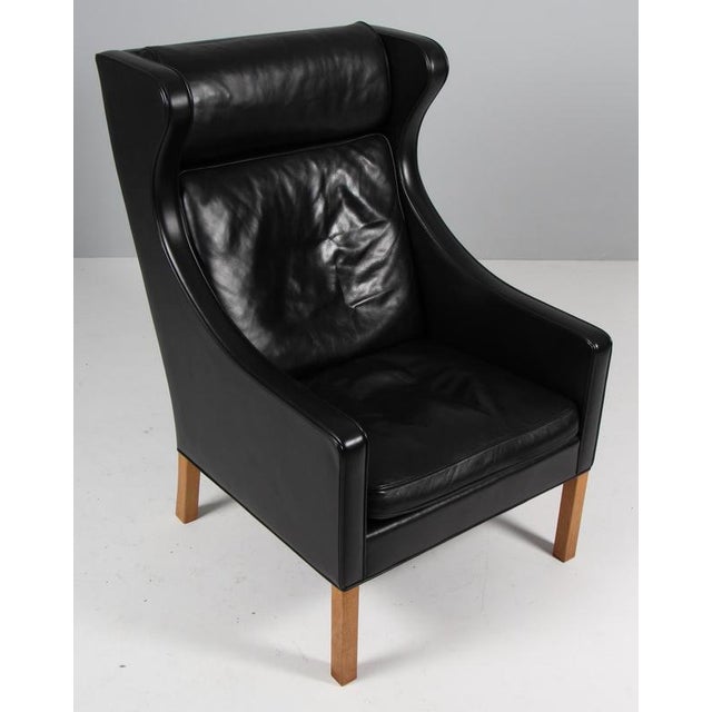 Børge Mogensen wingback chair in original Black leather upholstery. Legs in oak. Model 2204, made by Fredericia Furniture....