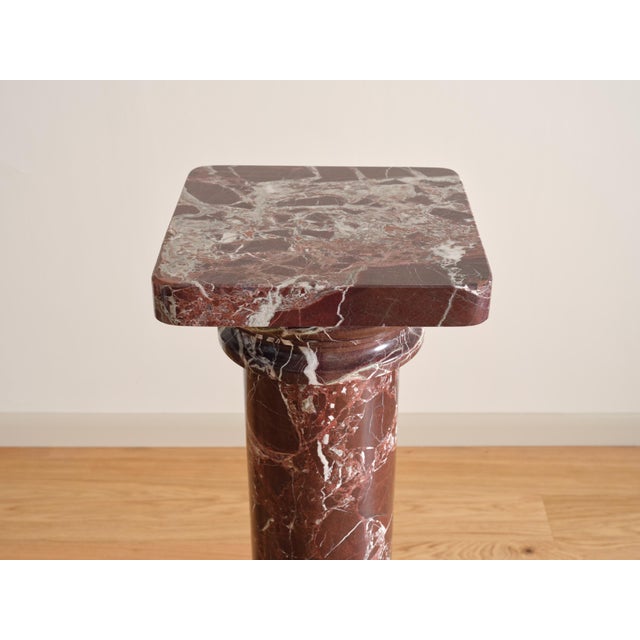 A vintage red marble pedestal featuring a classic column design with natural veining throughout. The rich tones and...