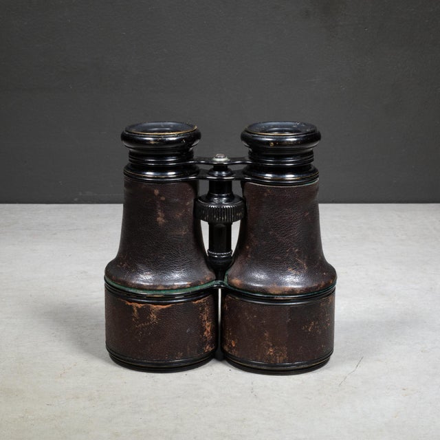 ABOUT An antique pair of leather wrapped expandable binoculars with enamel over brass body. The telescoping cylinders that...