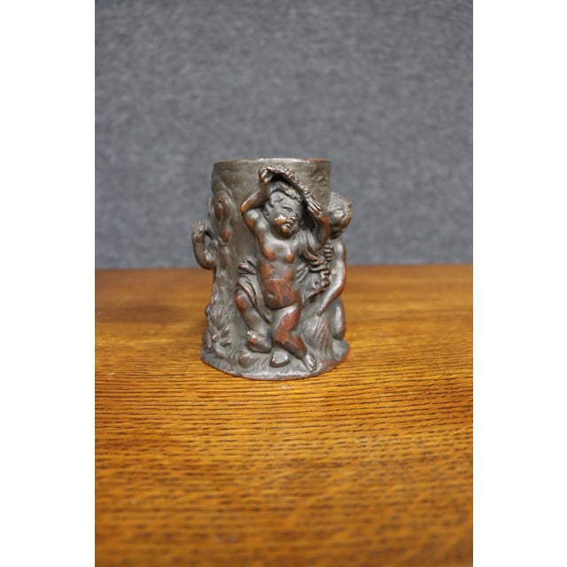 19th-century copper figural vase featuring multiple playful putti and cherubs in high relief, surrounded by scrolling...