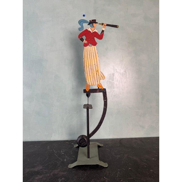 Charming vintage folk art kinetic sculpture featuring a hand-painted female figure dressed in a red jacket, striped skirt,...