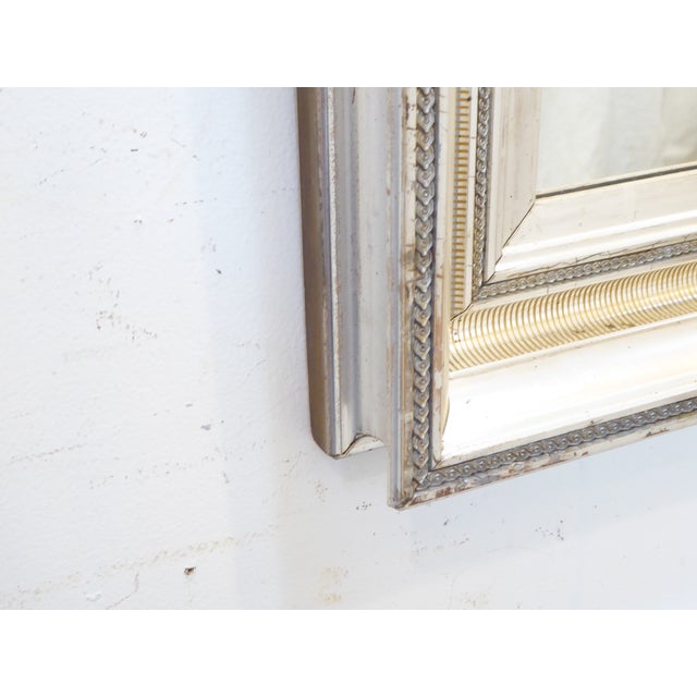 This 19th Century silverleafed mirror has different designs in the cover, including a stenciled reeded design and measures...