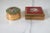 Set of two vintage brass pill boxes. The square one features a floral faux needlepoint. The round one features floral...