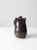 This hand-crafted vintage studio pottery pitcher, dated 1978, features a rich dark brown glaze, a gracefully curled...