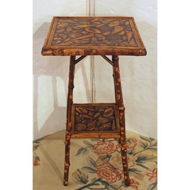 Circa 1880s 2-tier square bamboo side table, English. The surfaces now artisan decoupaged with shells. Decorative strut...
