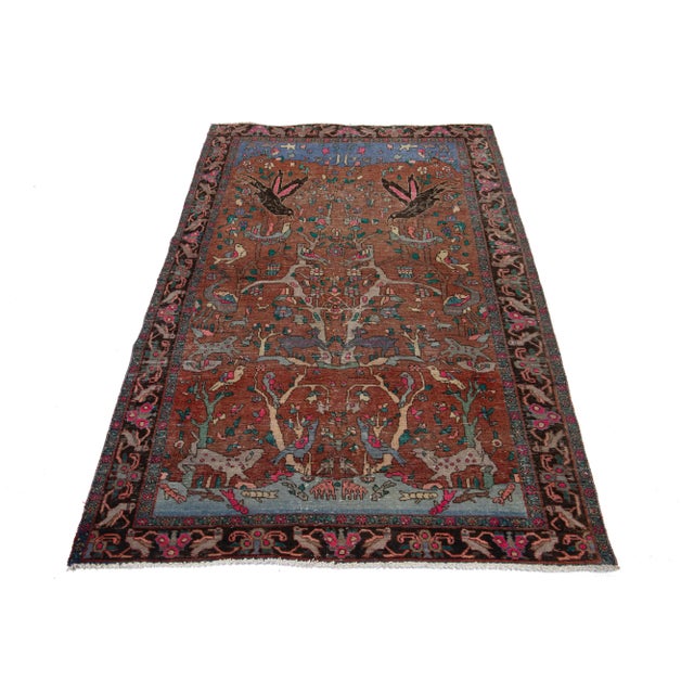 This vintage hand-knotted wool rug features a rust field with multicolor accents throughout the design. This rug measures...