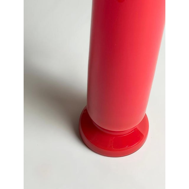 A red glass column vase from Empoli, Italy, crafted circa 1970s. Formed in cased glass, the vase features an inner layer...