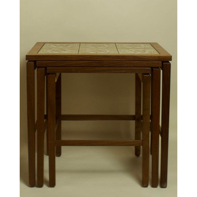 A set of three Danish Modern nesting tables crafted in teak with ceramic tile inlaid tops, Denmark, circa 1970s. The...