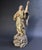 The polychrome wood carved sculpture depicts an angel standing on a pedestal of clouds, his left hand on his chest and his...