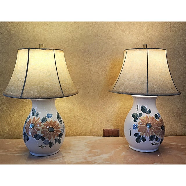 Pair of vintage ceramic lamps decorated with hand‑painted orange flowers, green foliage, and blue accents, paired with...