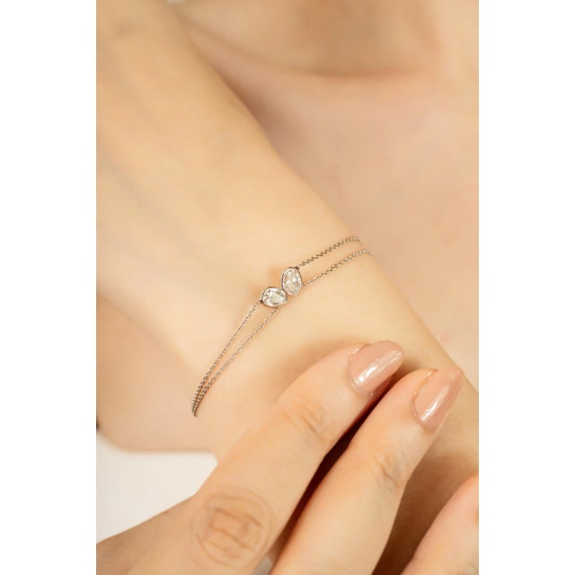 This elegant bracelet features two pear shaped diamonds totaling 1 carat, set in a sleek bezel setting that securely...