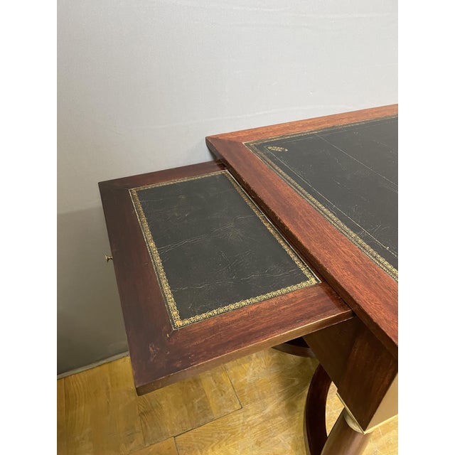 A mahogany flat desk with five drawers in the front, resting on four columns joined by a stretcher. Bronze ornamentation...