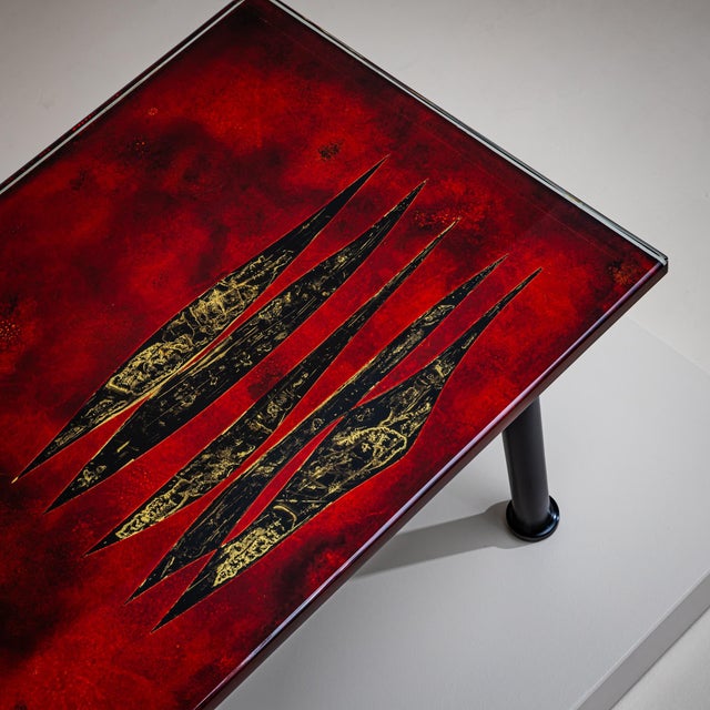 Rectangular coffee table on a black metal frame with a red enameled top. The surface features a decorative slotted...