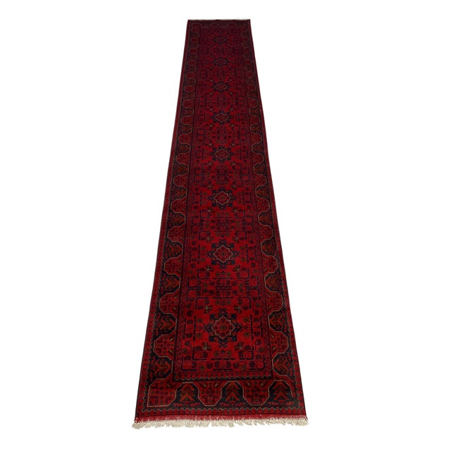 A row of diamond medallions runs down the rich red field of this long runner. Small branching motifs fill the spaces...