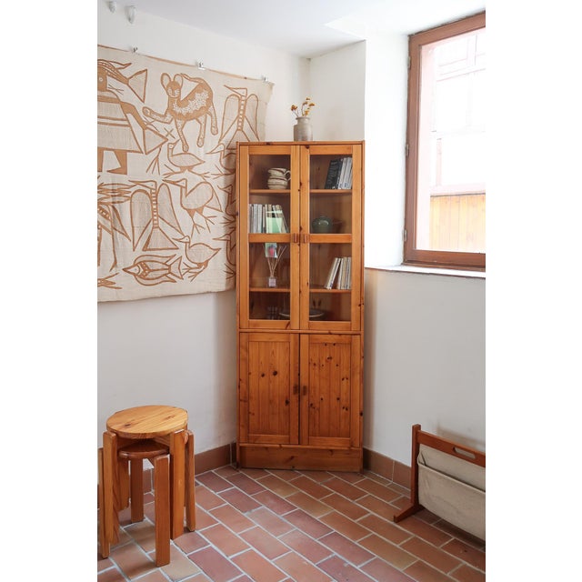 A glazed bookcase in solid pine, French rustic-modernist in the manner of Maison Regain. Two glazed doors above over four...