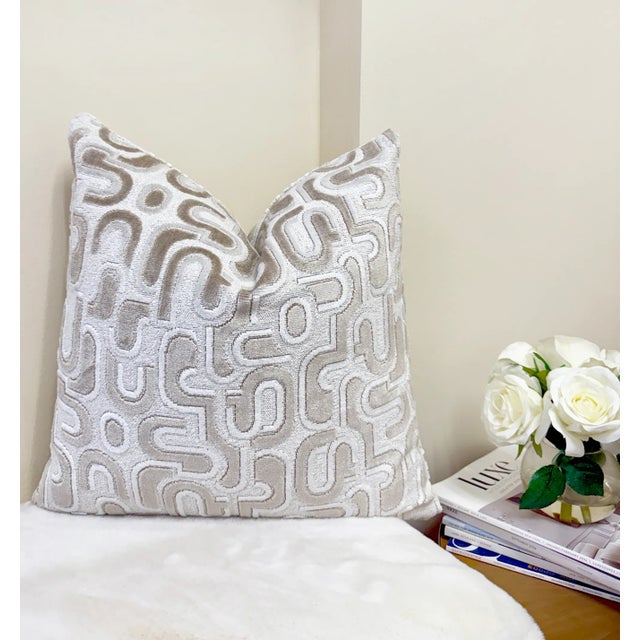 This pillow features a sculptural pattern of ivory and beige velvet shapes over a textured white bouclé background. The...