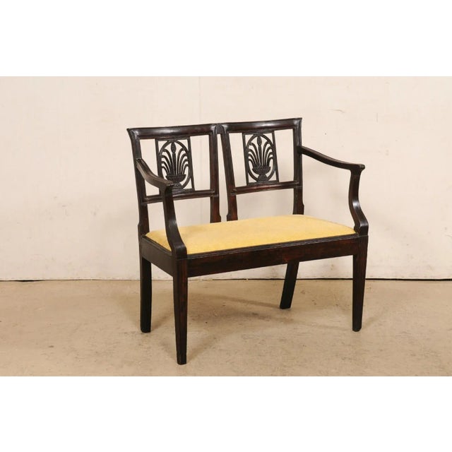 An Italian two-seat carved-wood settee from the turn of the 18th and 19th century. This antique tête-à-tête (loveseat)...