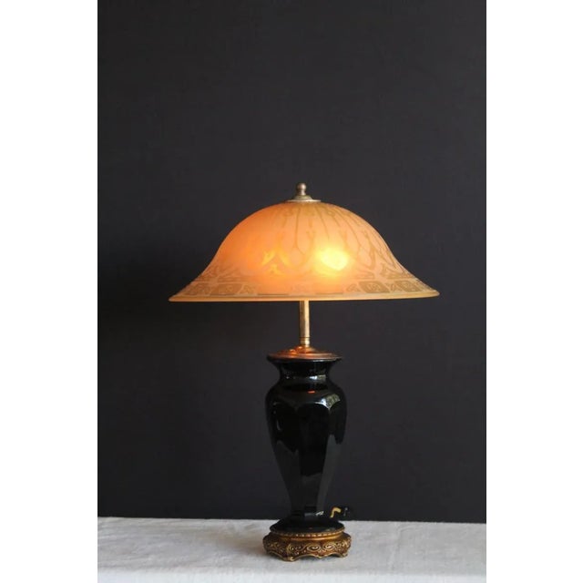 A stately Regency style table lamp. Base consisting of onyx glass and enameled and burnished metal. Shade molded etched...
